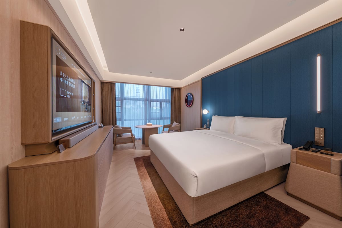 Een moderne hotelkamer met een groot bed, een bureau, een televisie en uitzicht op de stad.