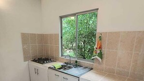 A kitchen with a gas stove, a window with a view of greenery, and a cartoon character doormat.