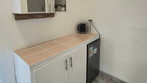 A kitchen with a built-in refrigerator, a coffee maker, and a cabinet with open doors revealing storage space.