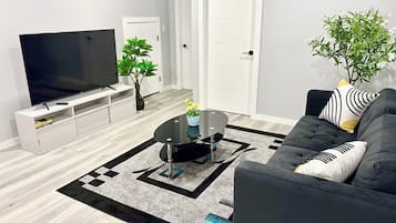 Een moderne woonkamer met een flatscreen televisie, een bank, een bijzettafeltje en een kamerplant.