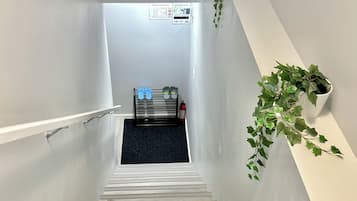 Een trap met een leuning, een brandblusser en een blauw tapijt aan de voet.