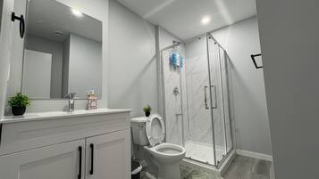 Un baño moderno con inodoro, lavamanos y ducha.