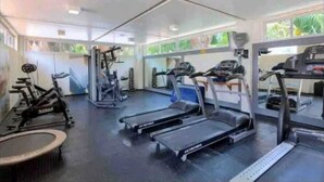Une salle de sport équipée de tapis de course, de vélos d’appartement et d’appareils de musculation.