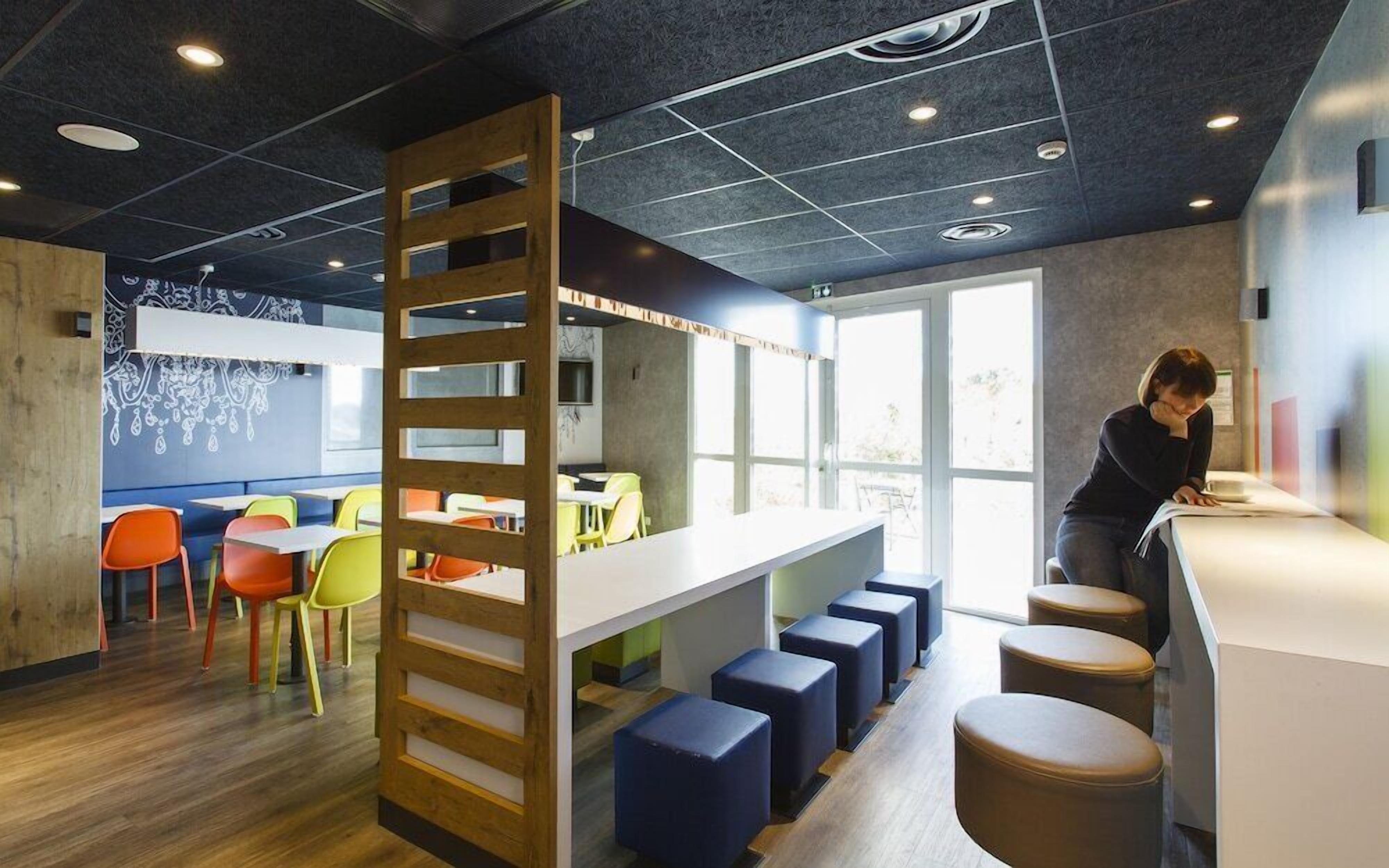 A modern interior with a wooden partition, colorful chairs, and a bar area.