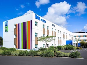 A modern hotel building with a white facade, vertical stripes, and a clear blue sky. - Ibis Budget Les Sables Olonne Sur Mer (Les Sables-d'Olonne)