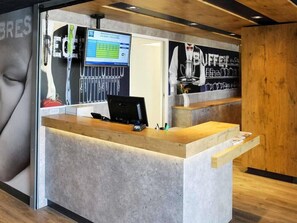 Bancada de recepção com computador, telefone e terminal de pagamento.