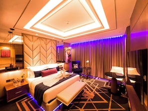 A modern hotel room with a large bed, a desk, a chair, a small table, and a mirror. - Planet Hollywood Thane City (Thane)