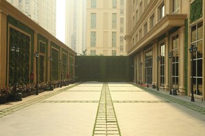 A courtyard with a central pathway, surrounded by buildings with large windows and columns. - Planet Hollywood Thane City (Thane)