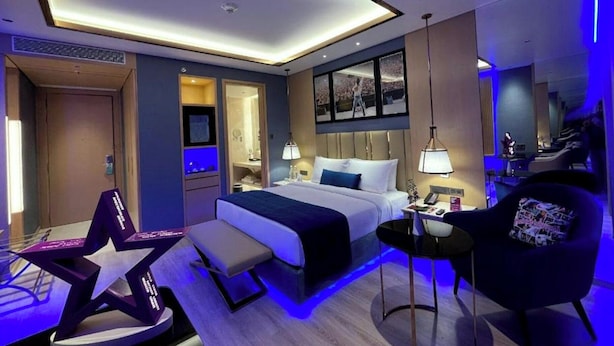 Ein modernes Hotelzimmer mit Bett, Nachttisch, Lampe, Stuhl und einer sternförmigen Dekoration.