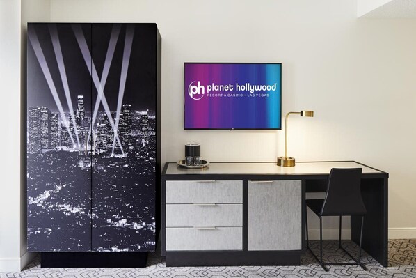 Een hotelkamer met een bureau, een stoel, een flatscreen televisie en een kast met een stadsgezicht dessin.