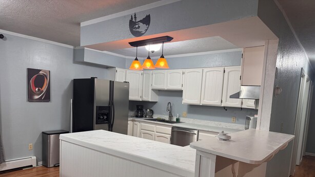 A modern kitchen with white cabinetry, a central island, and pendant lighting. - Central Fairbanks 3BR/2BA,  King Bed,  Sleeps 6, Free Laundry (Fairbanks)