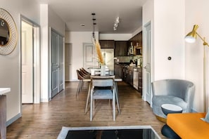 Eine moderne Küche mit dunklen Schränken, ein Essbereich mit Tisch und Stühlen sowie eine Wohnbereich mit Sofa und Lampe.