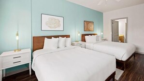 Una habitación de hotel con dos camas, ventilador de techo y obras de arte en las paredes.