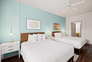 Ein Hotelzimmer mit zwei Betten, einem Deckenventilator und Bildern an den Wänden.