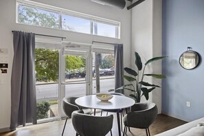 A room with a dining table, chairs, a plant, a mirror, and large windows with curtains. - Sports Illustrated Resorts Nashville Music Row (Nashville)
