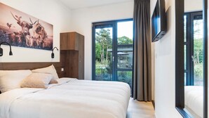 Ett modernt hotellrum med en stor säng, en tavla med djurmotiv, en tv och utsikt över omgivningarna.