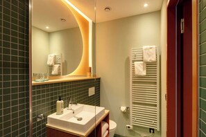 Ein modernes Badezimmer mit einer Duschkabine, einem weißen Waschbecken mit Seifenspender und einem Handtuchhalter.