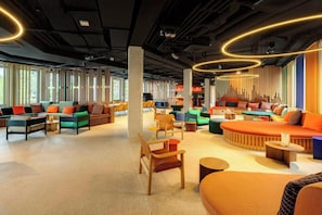 A modern lounge area with seating arrangements, a coffee table, and a wall-mounted sound system. - Dein Apart (Unterfoehring)