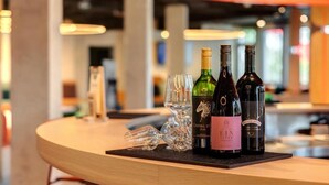 A bar area with a wooden counter, wine bottles, and glasses. - Dein Apart (Unterfoehring)