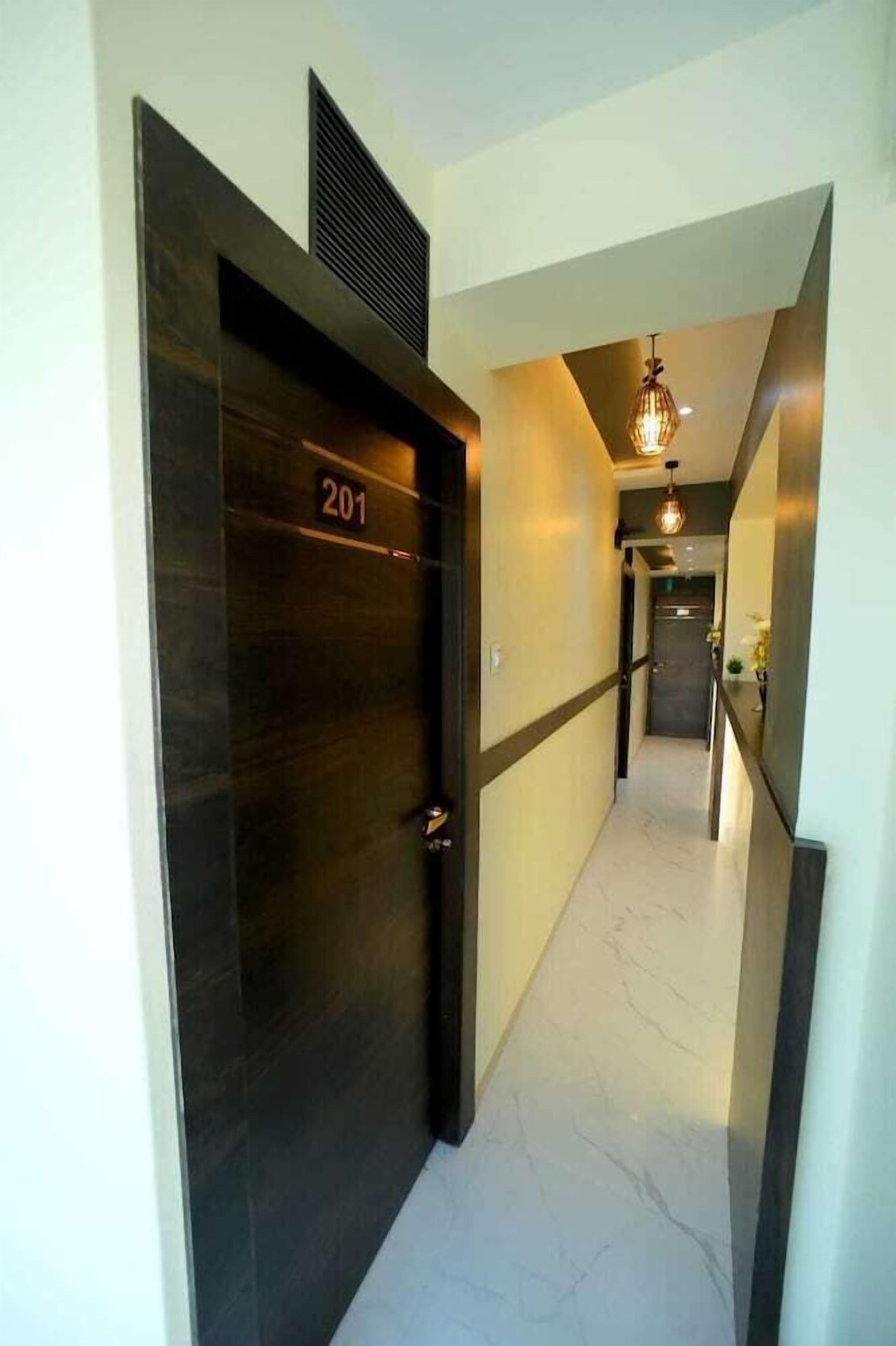 A hallway with a dark door marked '201', a light-colored tiled floor, and a hanging light fixture.
