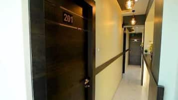 A hallway with a dark door marked '201', a light-colored tiled floor, and a hanging light fixture.
