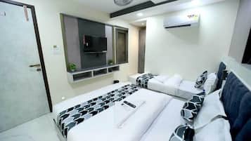 A hotel room with a bed, a TV, a wall-mounted air conditioner, and a door.