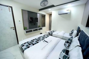 A hotel room with a bed, a TV, a wall-mounted air conditioner, and a door. - N.m. Hotel Mumbai (Mumbai)
