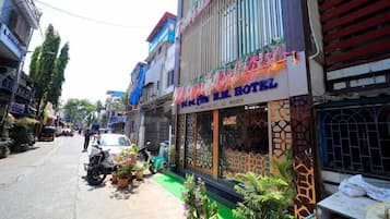A hotel with a signboard, a gated entrance, and potted plants along the sidewalk.