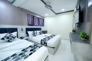 A hotel room with two beds, a TV, a ceiling fan, and a small plant. - N.m. Hotel Mumbai (Mumbai)