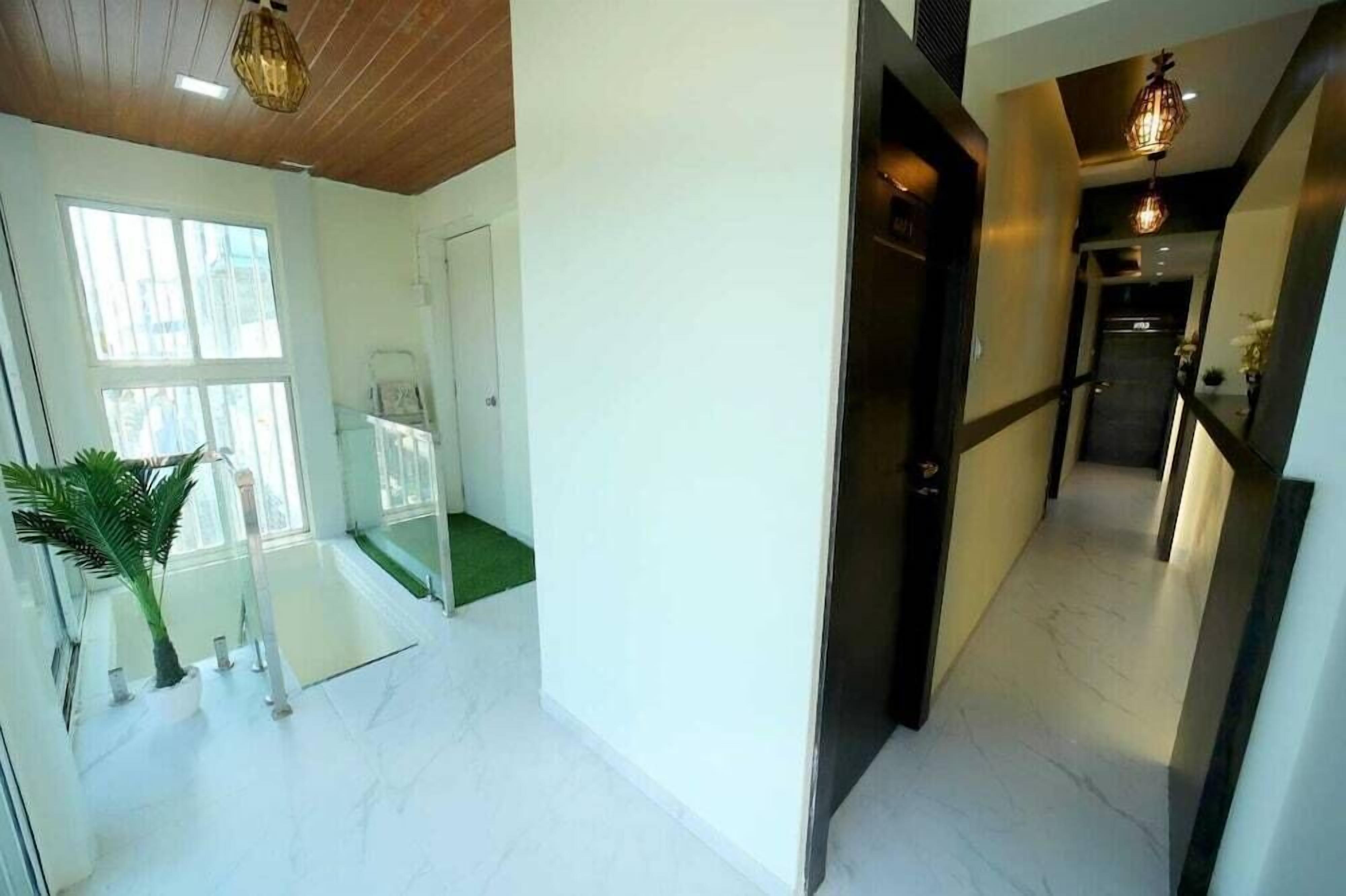 A modern hotel interior with a glass staircase, a hallway with a door, and a staircase leading to a landing.