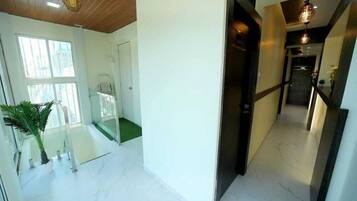 A modern hotel interior with a glass staircase, a hallway with a door, and a staircase leading to a landing.