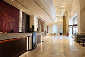 Eine Hotelhalle mit Empfangstresen, Sitzgelegenheiten und einem Chandelier.