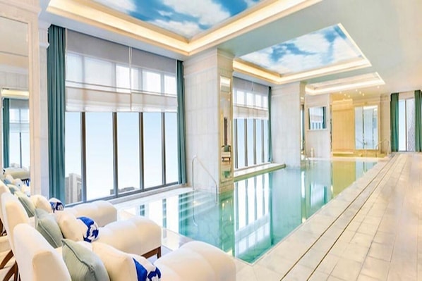Eine Hotelhalle mit Pool, Sitzgelegenheiten und großen Fenstern.