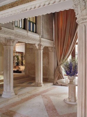 Un intérieur avec des colonnes, un escalier et une vue sur l’extérieur.