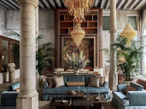 A luxurious lobby with a blue sofa, a large chandelier, and columns. - Orient Express Palazzo Dona Giovannelli (Venice)