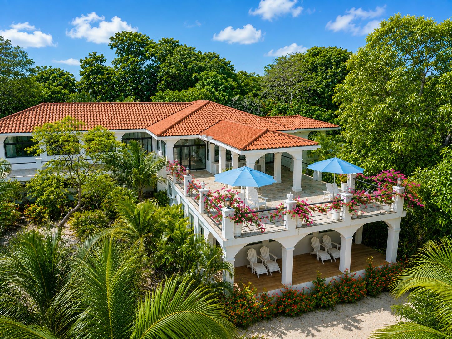 A two-story building with a red-tiled roof, white columns, and a covered outdoor seating area with umbrellas.