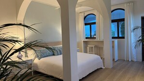 A bedroom with a bed, a desk, and a window with curtains.