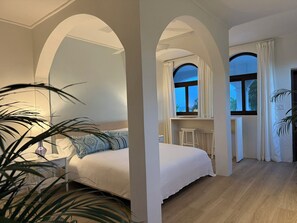 A bedroom with a bed, a desk, and a window with curtains. - The Hacienda - Studio West (Utila)
