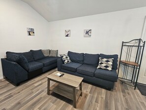 A living room with two dark sofas, a wooden coffee table, and a metal chair.