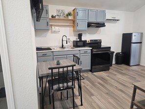 A compact kitchen with grey cabinets, a built-in microwave, a stove, and a refrigerator.