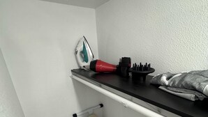 Un angolo lavanderia piccolo e ben organizzato, con un asse da stiro, un ferro e una spazzola.