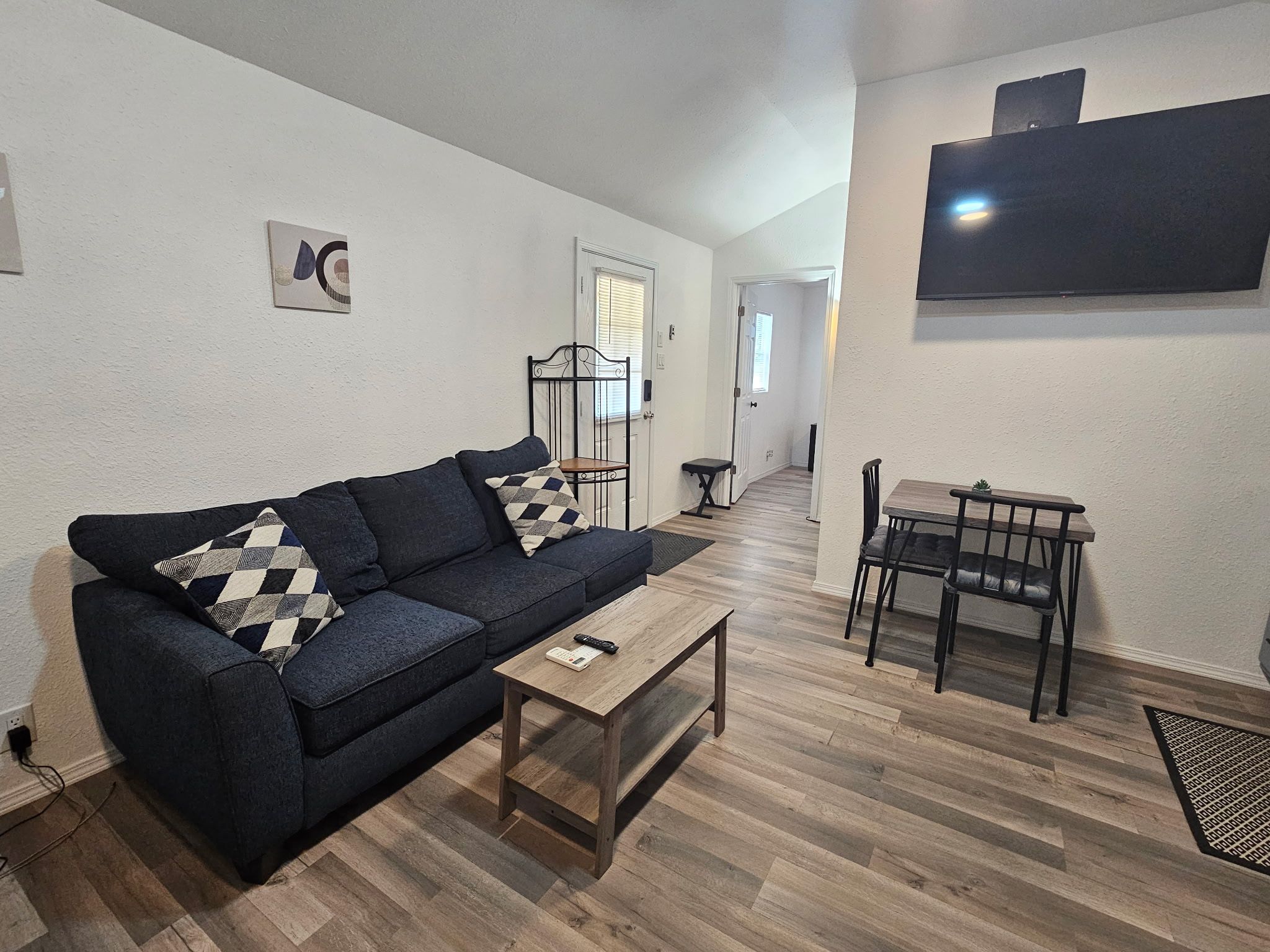 A living room with a sofa, coffee table, and a TV mounted on the wall.