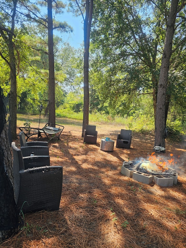 Un espacio de estar al aire libre con mobiliario de mimbre y una chimenea.