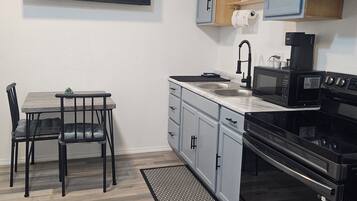 A modern kitchen with a flat-screen TV, a dining table with chairs, and a built-in oven.