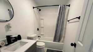 Un bagno con il water, lavandino, vasca e tenda da doccia.