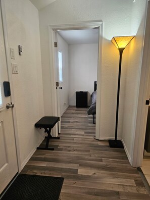 Un pasillo con un banco, una lámpara y una puerta que da a otra habitación.