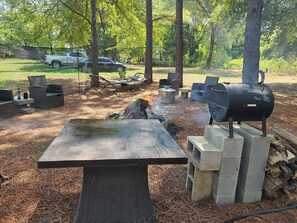 Un espacio al aire libre con una parrilla, asientos y una mesa.