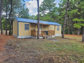 A small wooden cabin with a blue roof, surrounded by trees.