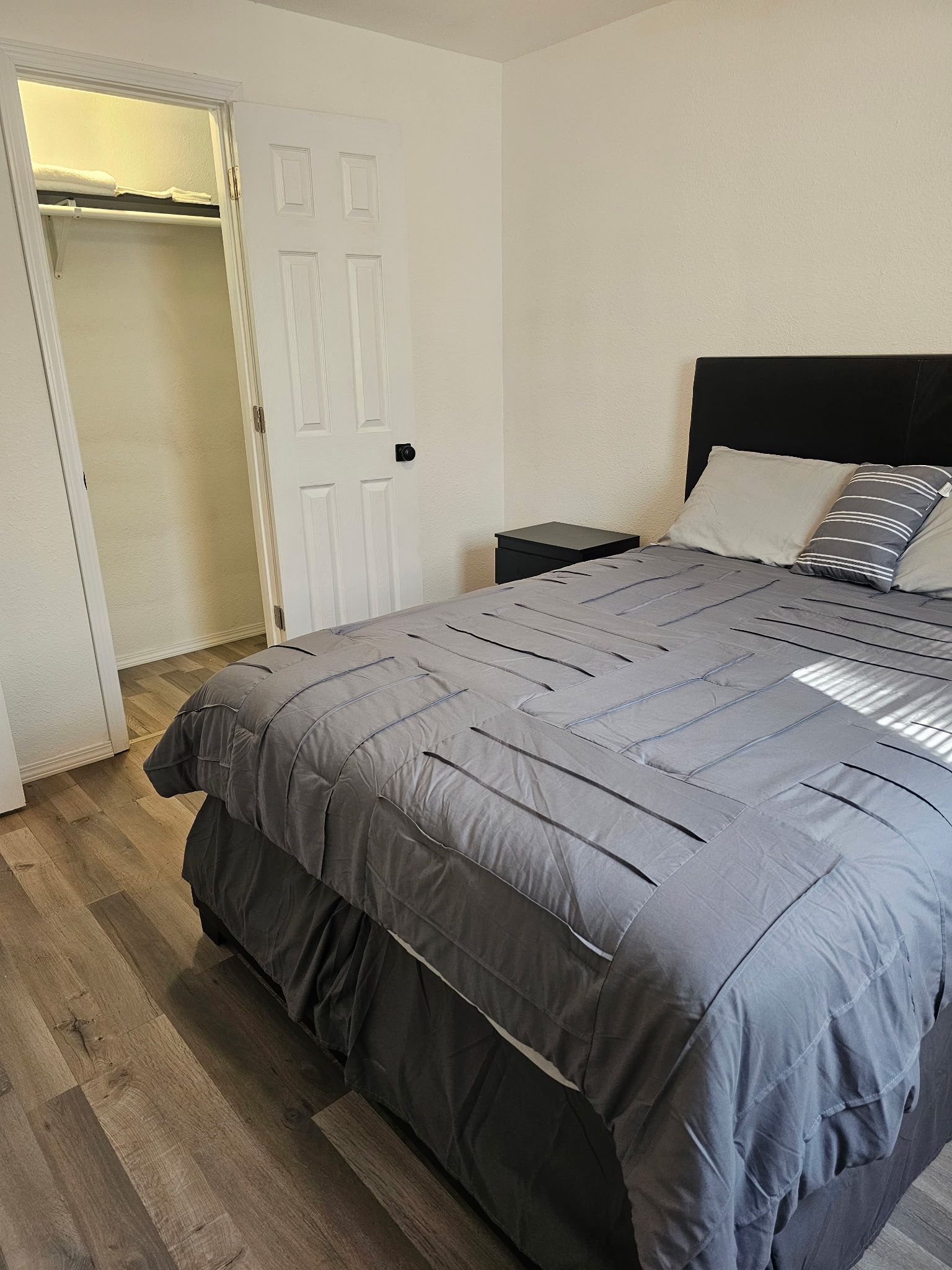 A bedroom with a bed, a nightstand, a closet, and a door.