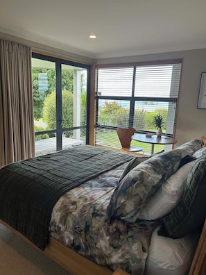 Ein Schlafzimmer mit einem großen Bett, einer Schiebeglasdoor zu einem Balkon und einem kleinen Tisch mit einer Pflanze.